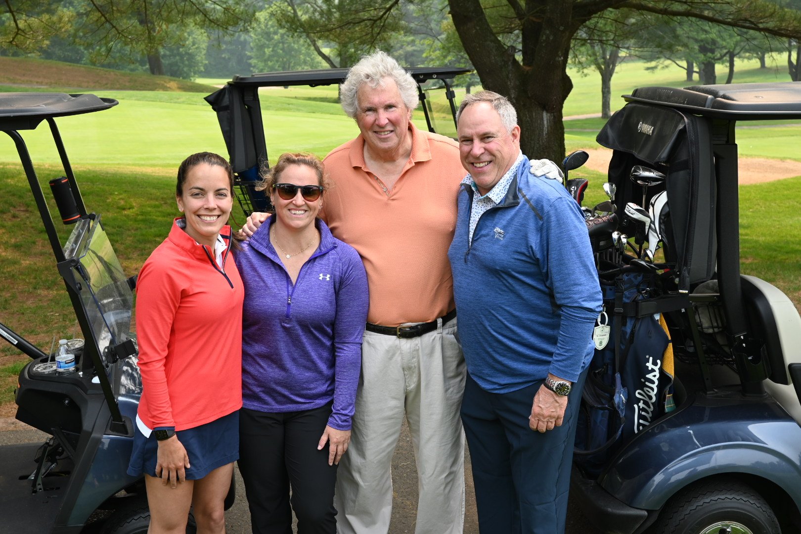 4 individuals standing in front of golf cart